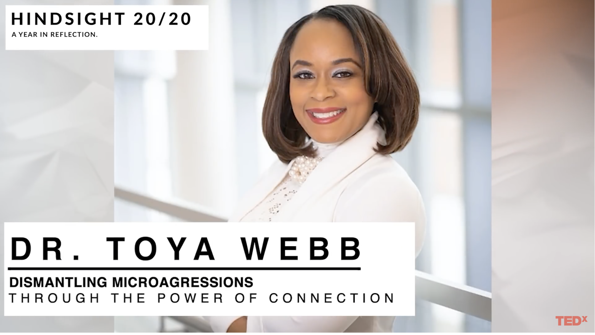 Professional African American woman wearing all white with arms crossed smiling at camera